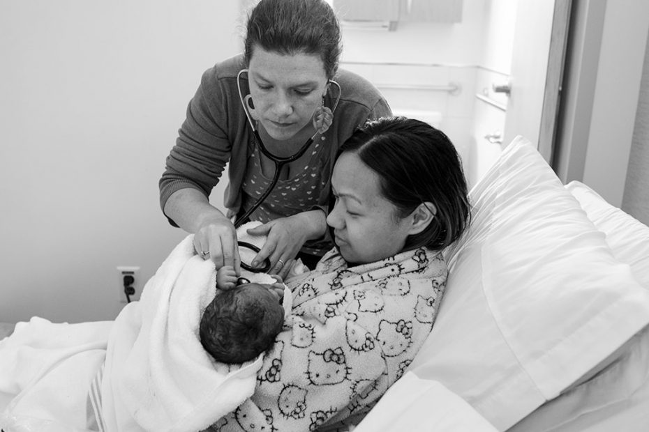 Midwife examining a newborn that is being held by mother
